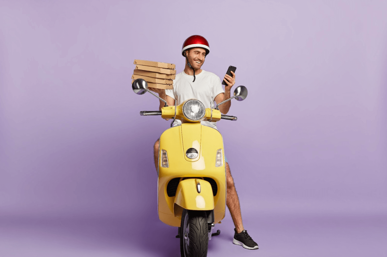 a delivery driver holding pizza boxes and a phone while sitting on a scooter